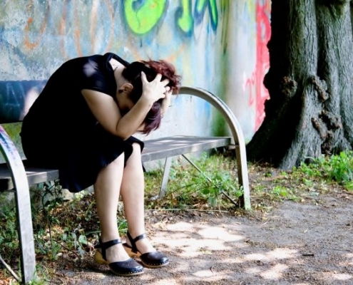 burnout -eine frau sitz auf einer bank sie ist sehr verzweifelt-thema - psychologische beratung krisen bewältigung
